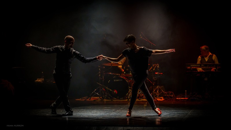 Duo de danseurs en pleine figure, les musiciens en fond de scène