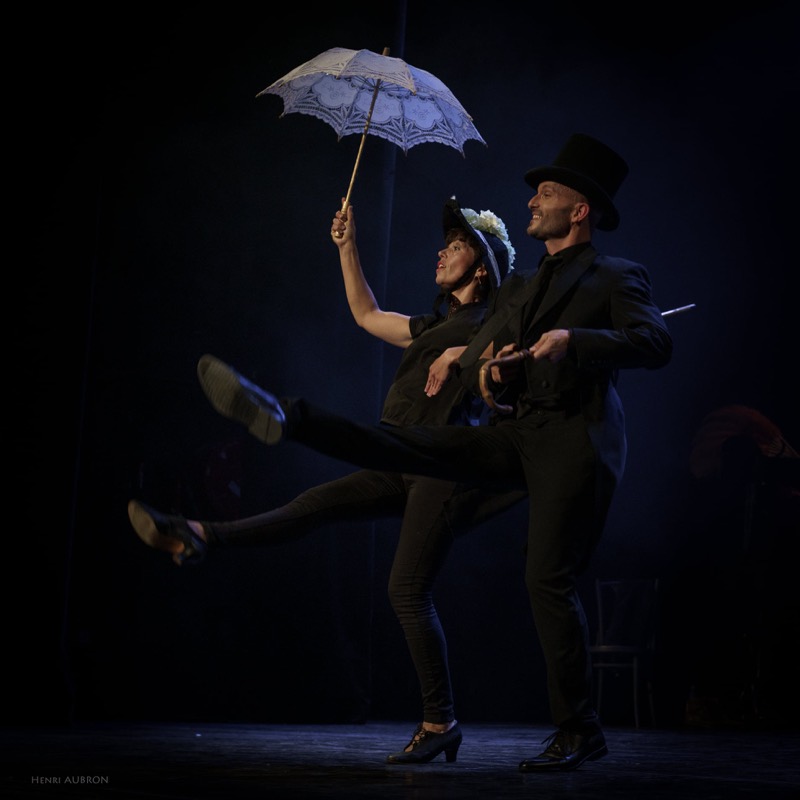 Couple de danseurs à l'ombrelle, chapeau haut de forme et jeté de jambe
